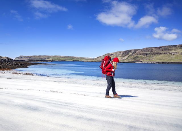 A walker on a beautiful sandy beach under a blue sky