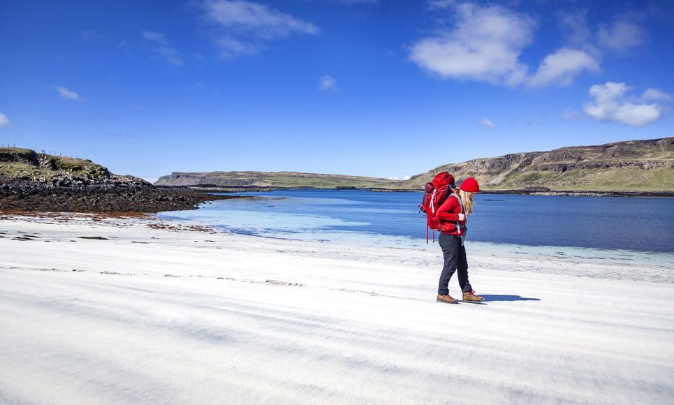 A walker on a beautiful sandy beach under a blue sky