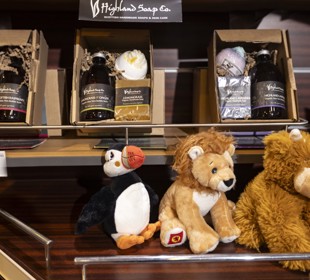 soap gift boxes sitting in a shelf of the shop above a toy puffin, lion and highland cow