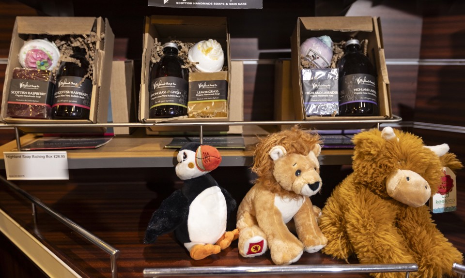 soap gift boxes sitting in a shelf of the shop above a toy puffin, lion and highland cow