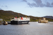 The Caledonian MacBrayne ferry to Barra sitting in the bay next to the rugged stone Kisimul Castle.