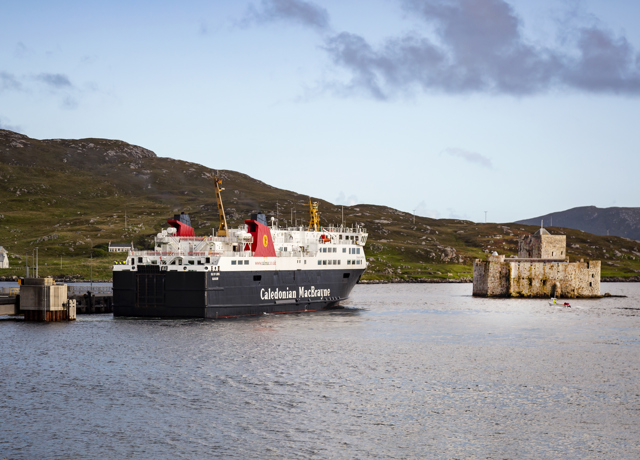 The Caledonian MacBrayne ferry to Barra sitting in the bay next to the rugged stone Kisimul Castle.