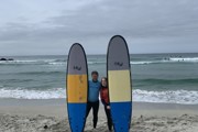 two surfers posing on the beach each holding a surfboard