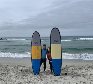 two surfers posing on the beach each holding a surfboard