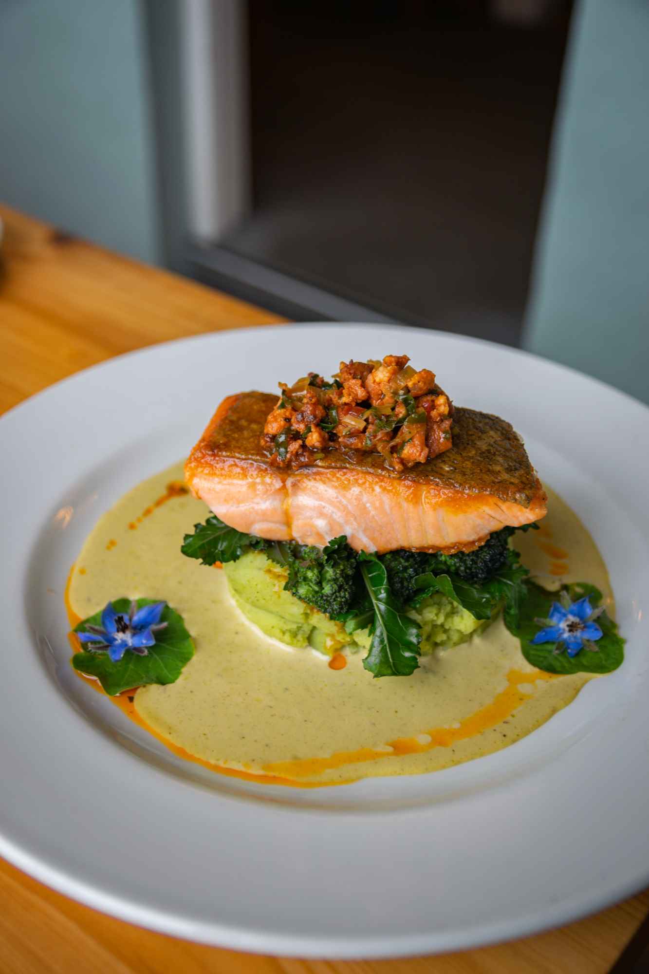 A restaurant prepared salmon fillet on a bed of vegetables with a creamy sauce.