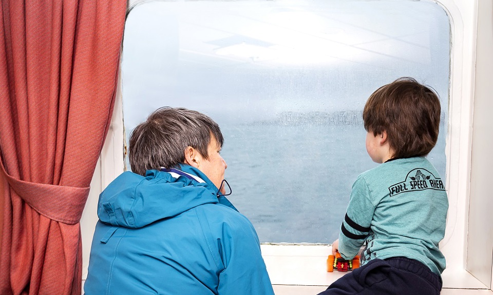 woman and little boy looking out of window