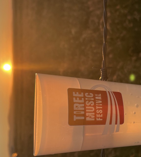 branded Tiree Music Festival cup with the sunset in the background. 