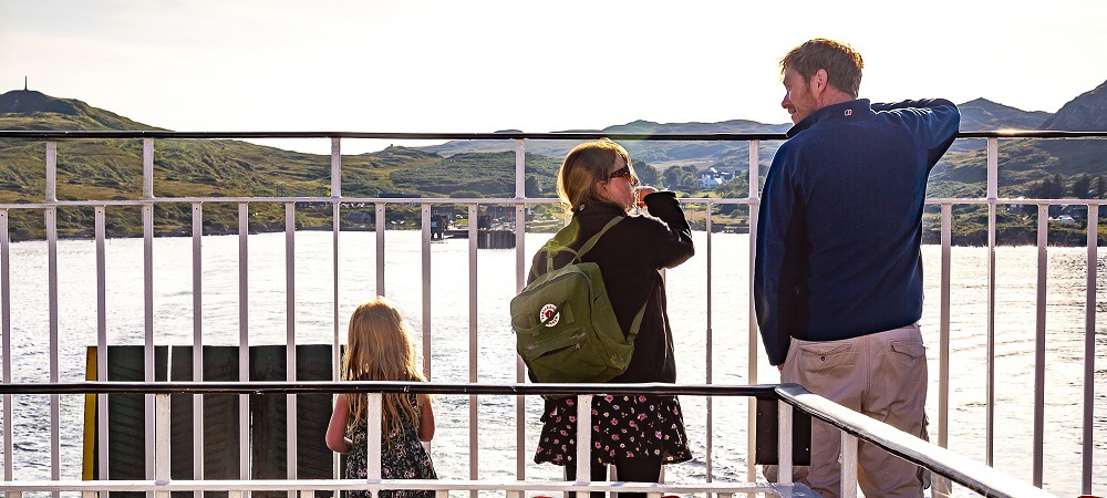 Father and his daughters standing on deck looking out to sea