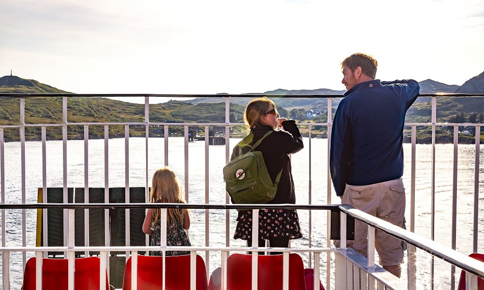 Father and his daughters standing on deck looking out to sea