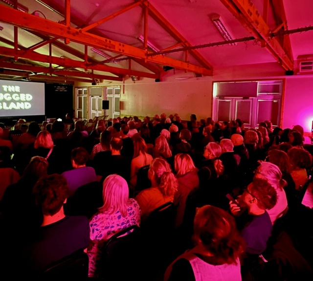 Audience gathered in a venue watching a film screening as part of the Sea Change Film Festival in Tiree.