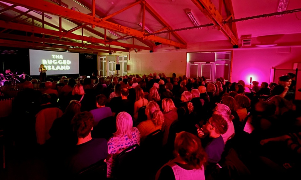 Audience gathered in a venue watching a film screening as part of the Sea Change Film Festival in Tiree.