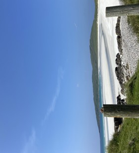 steel gate leading to a beach with white sand and blue water