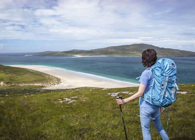 A hiker admiring the view down to the golden sandy beaches and rolling hills in the distance