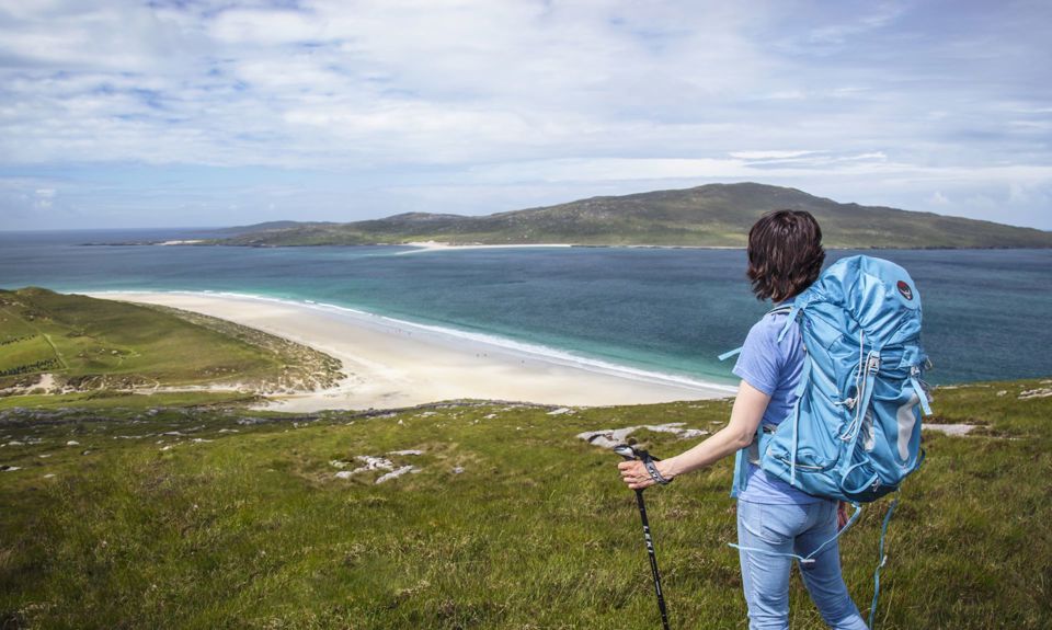 A hiker admiring the view down to the golden sandy beaches and rolling hills in the distance