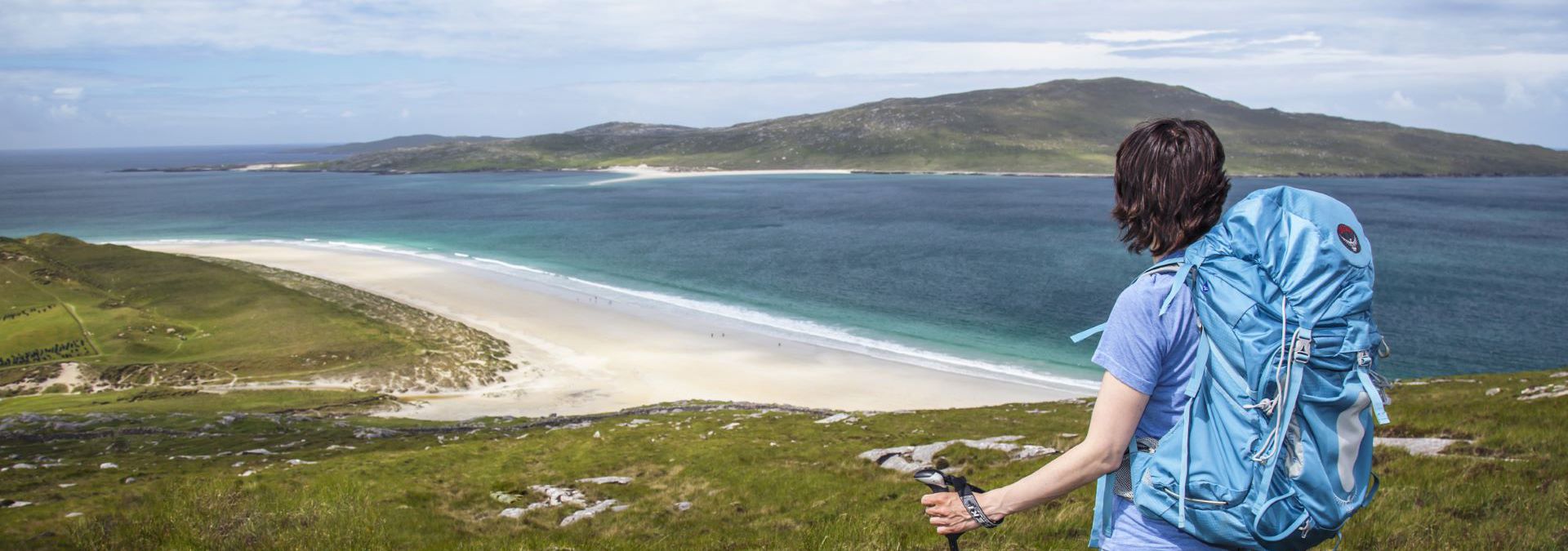 A hiker admiring the view down to the golden sandy beaches and rolling hills in the distance