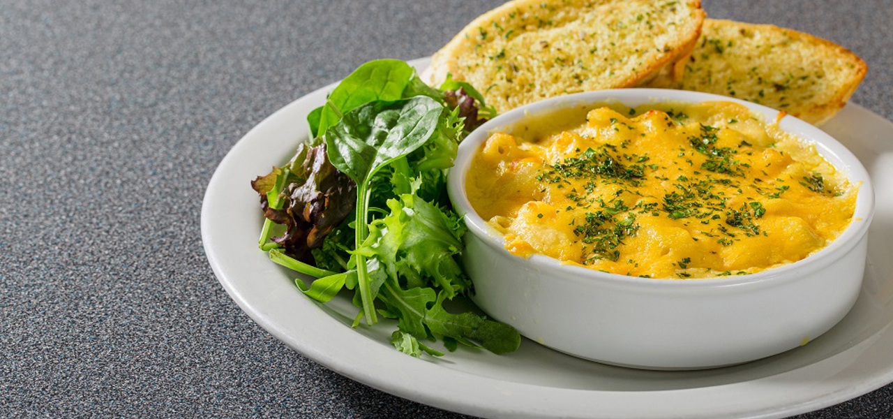 A plate of macaroni cheese served with side salad and garlic bread.