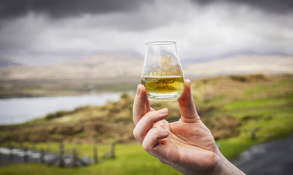 A glass of whisky being held aloft outdoors
